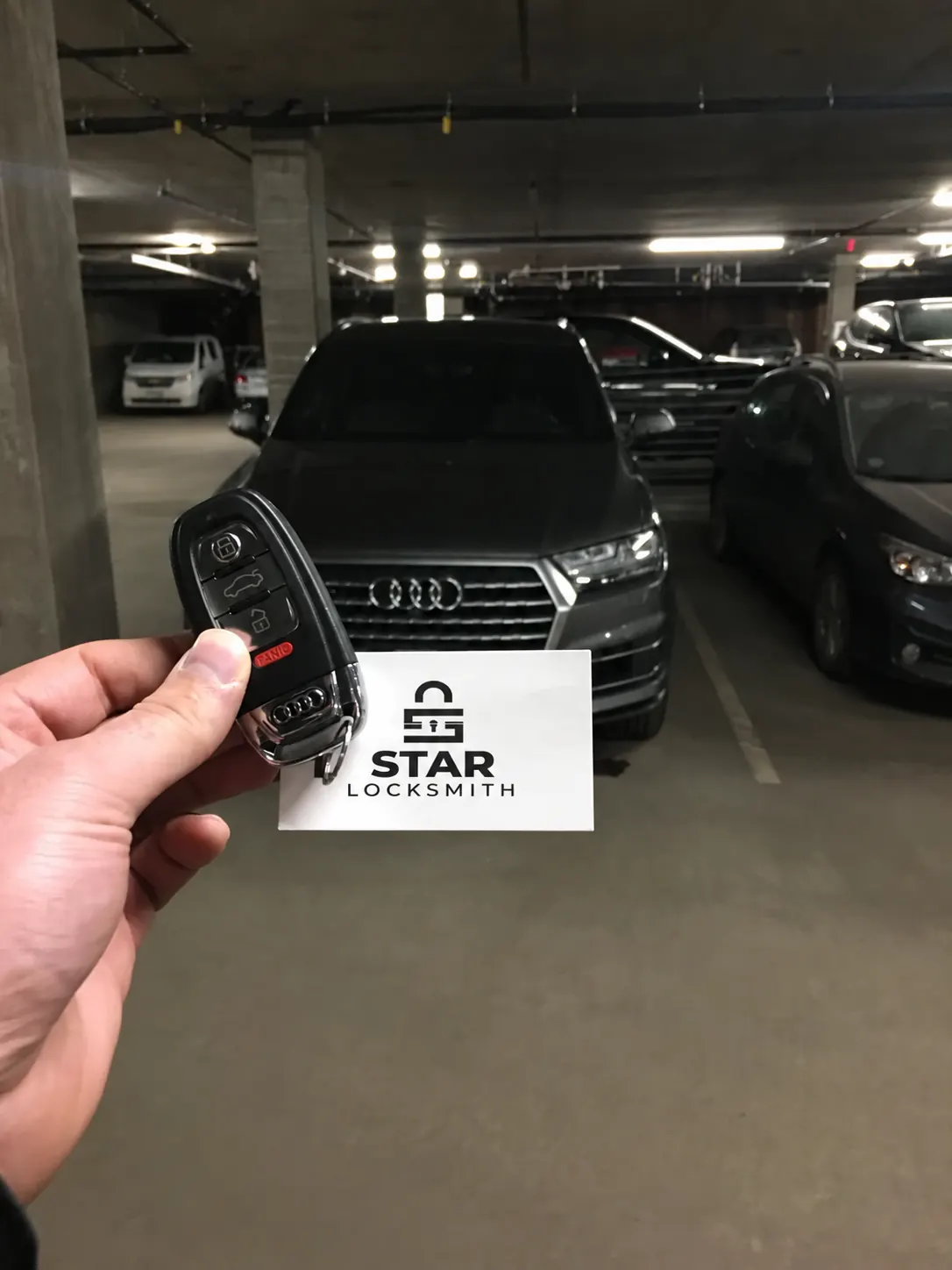 Audi key fob and Star Locksmith card in front of an Audi